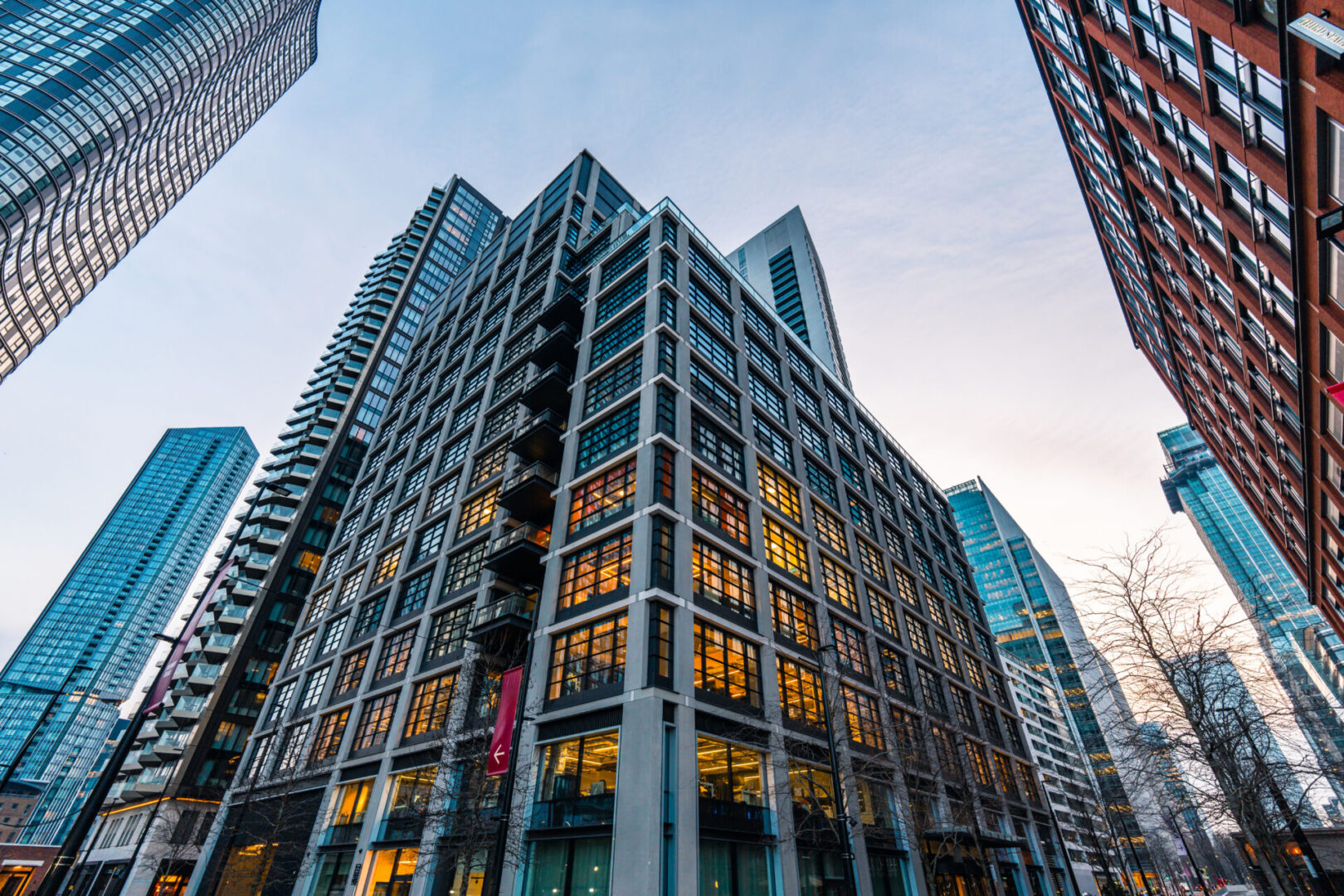 City skyscrapers at dusk with illuminated windows.
