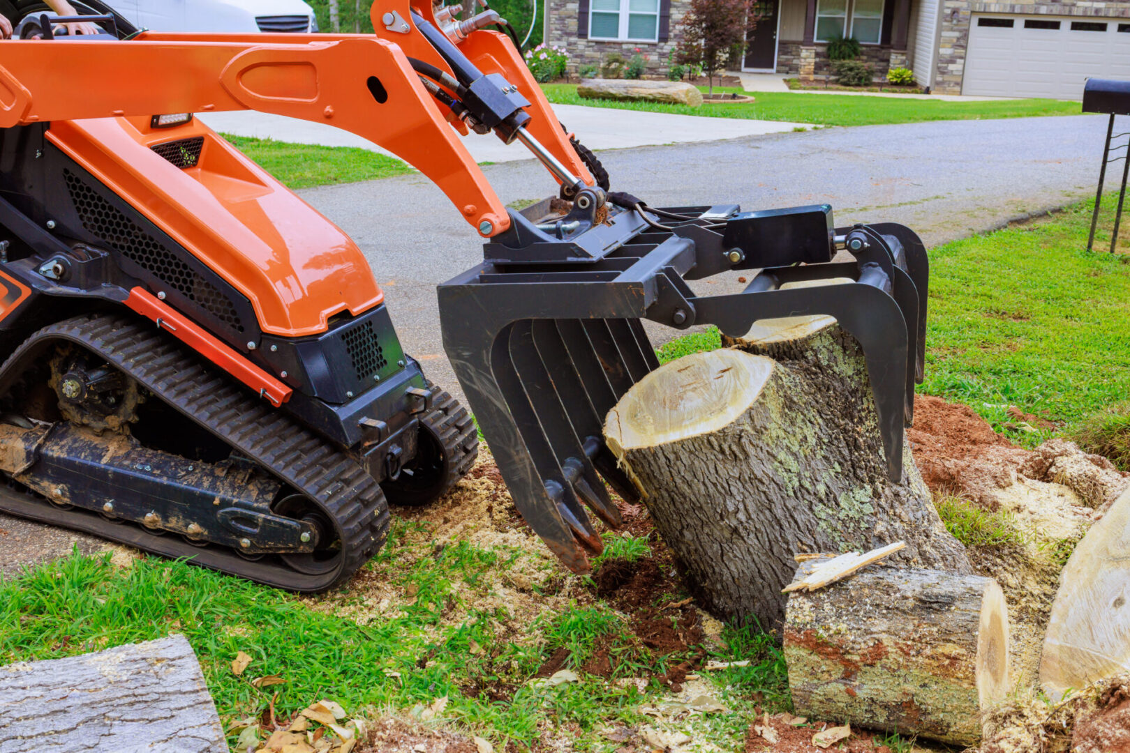Mini excavator lifting large tree stump.